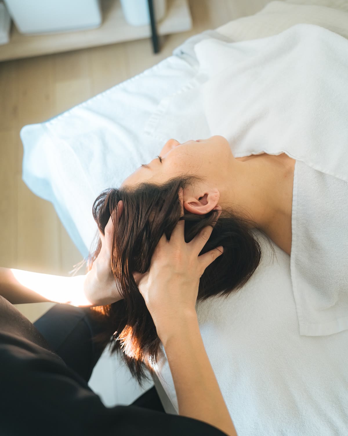 朝の光が差しこむ部屋で、ヘッドスパを受けている女性
